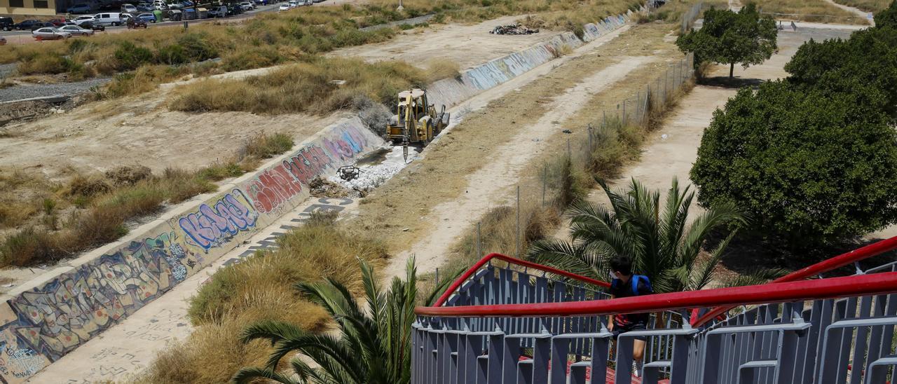 Un joven observa desde el puente rojo el trabajo de la excavadora para demoler un viejo canal de desagüe.