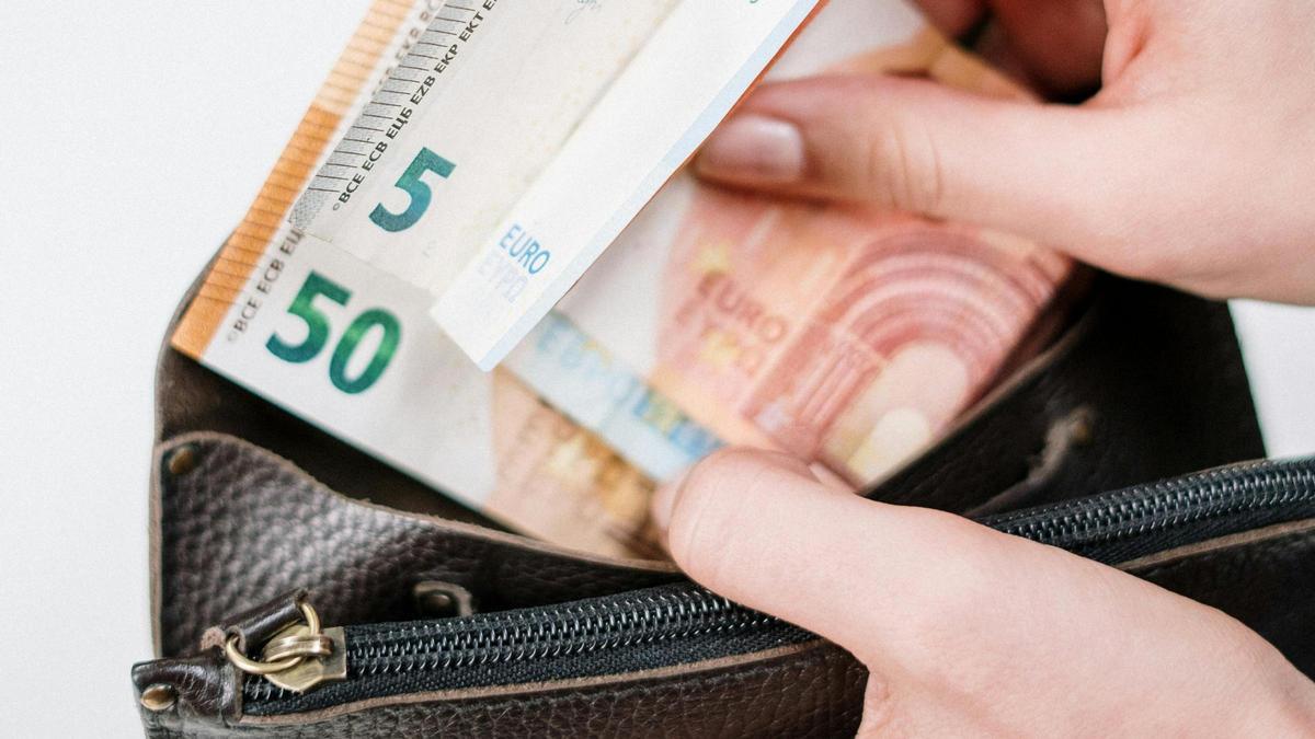 Una persona guarda billetes de euro en su cartera.