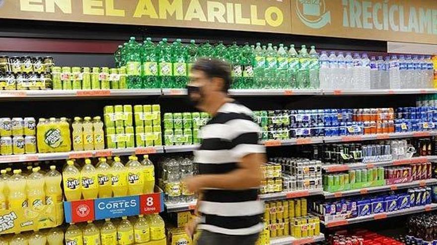 Un client passa per davant del  lineal de refrescos on s&#039;observa un cartell que explica on dipositar aquests envasos |