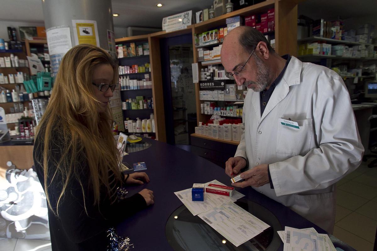 Un farmacéutico cortando el precinto de una caja de medicamentos, práctica que pronto quedará en el olvido.