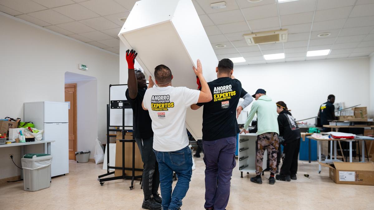 Un grupo de trabajadores carga con un mueble.