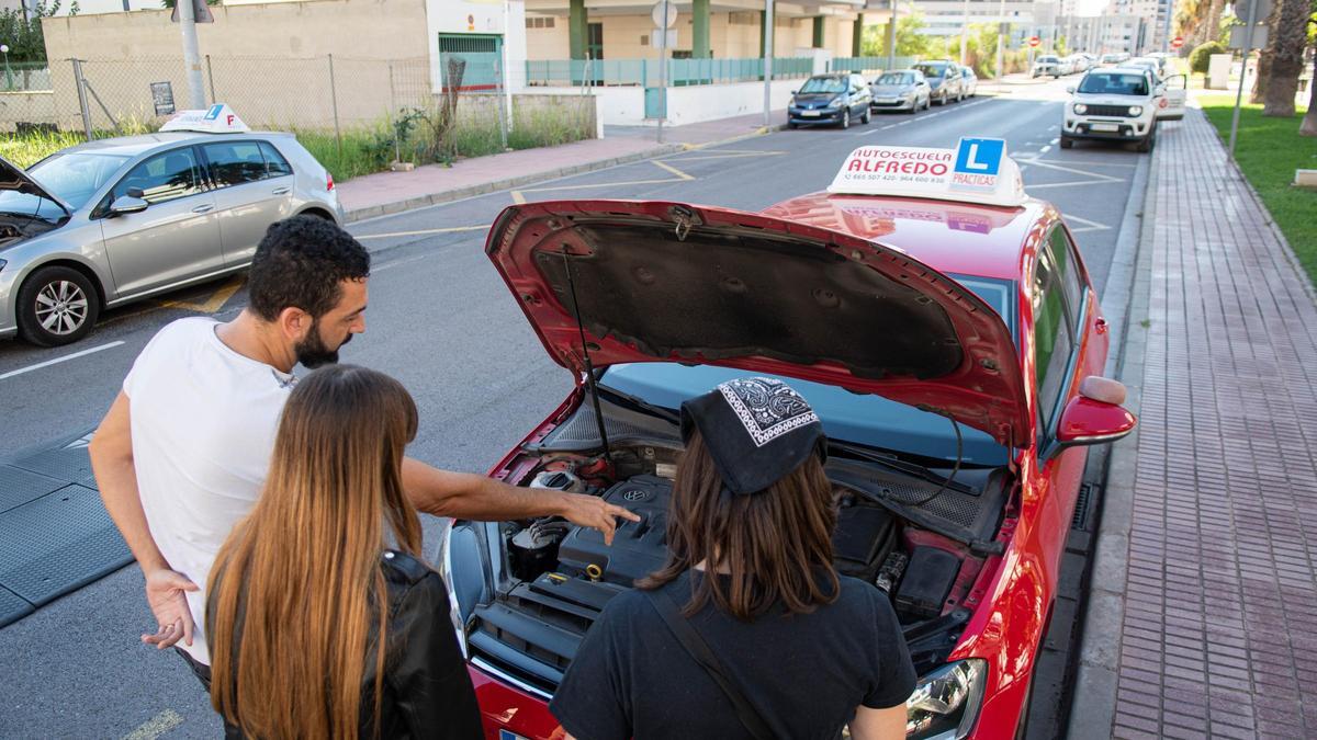 Un profesor de autoescuela indica a dos jóvenes las piezas que hay debajo del capó del coche, en una foto de archivo.