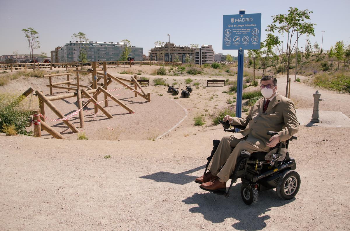 Javier Font posa ante un cartel y una zona inaccesibles para las personas con discapacidad en el parque de La Gavia. 