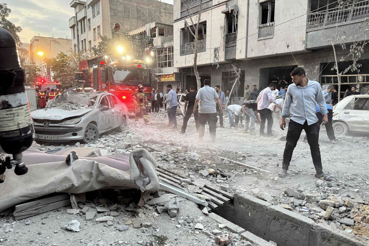 Personas y personal de emergencia se reúnen frente a un avión que fue alcanzado por un ataque israelí en Teherán el 13 de junio de 2025. 