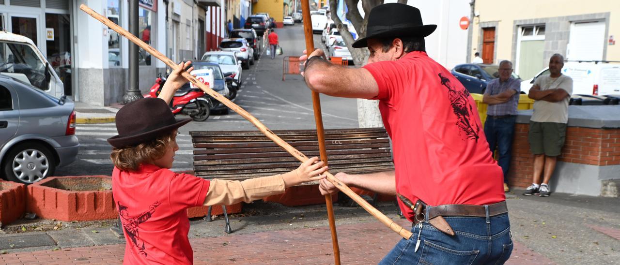 Un niño practica el garrote canario junto a uno de los monitores de la Escuela Maestro Paquito Santana.