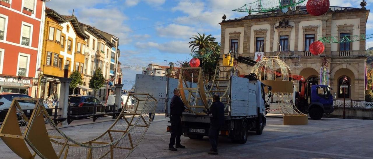 Operarios instalando ayer las últimas piezas, como el arco de la plaza del Ayuntamiento y las hojas de acebo. | Alicia García-Ovies