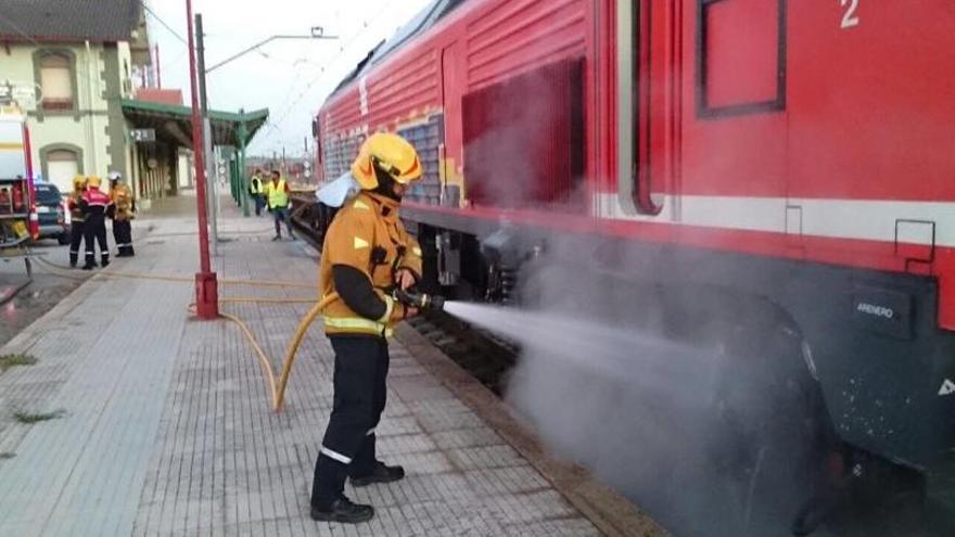 Un bombero refrigerando los ejes de la locomotora a las siete y media de esta mañana en la estación del ferrocarril de La Encina