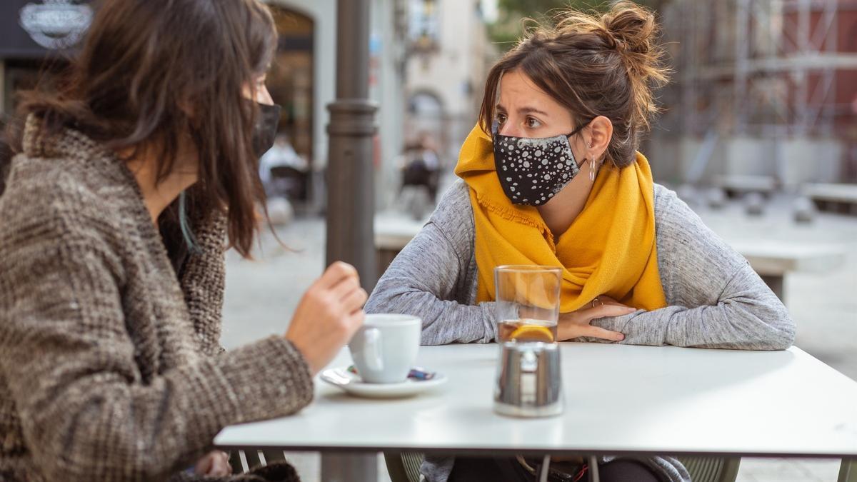 Una imagen de archivo de dos mujeres tomando un café en una terraza con la mascarilla puesta