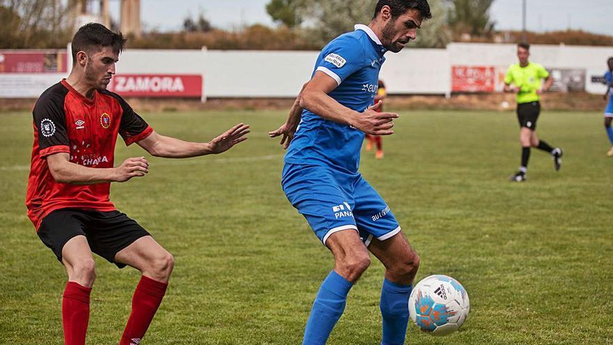 Un jugador del CD Villaralbo protege el cuero ante la entrada de un rival.