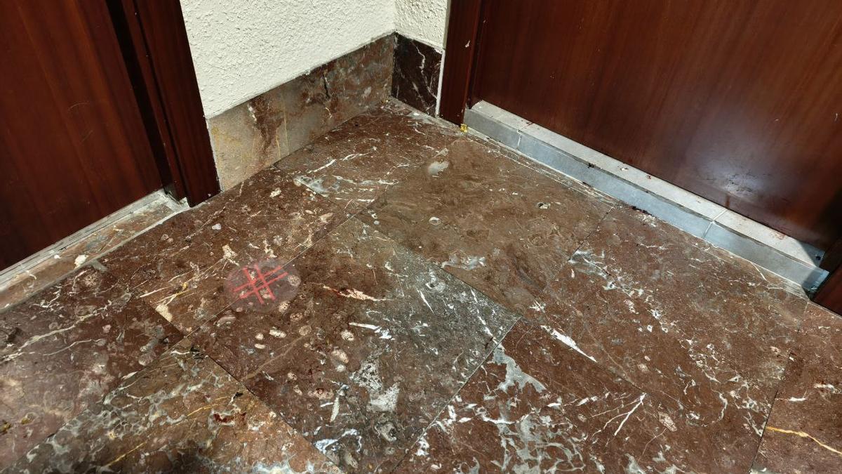 Restes de sang i la marca de la policia científica a terra davant de la porta de la casa.