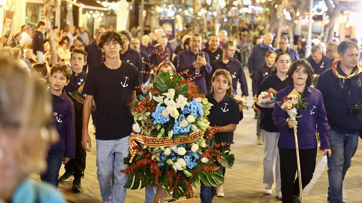 Festeros llevan flores durante la ofrenda.
