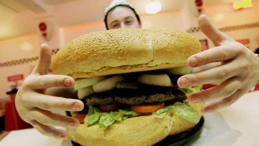 Un hombre echa las manos a una hamburguesa.