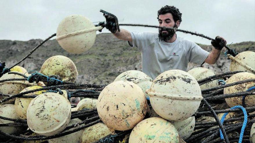 Un pescador desenreda los amontonados cables cobre y boyas.