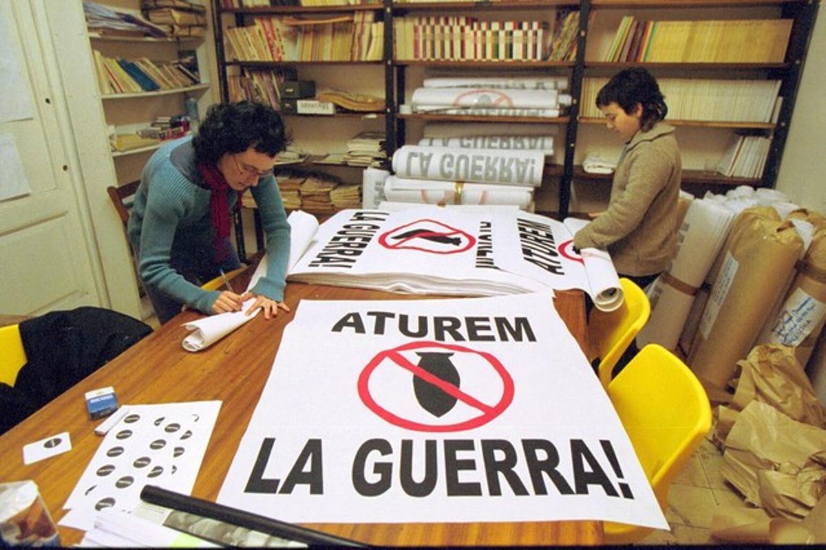 Dos activistas de la plataforma Aturem la guerra, Ruth y Reyes, preparan pancantas para la manifestación, con el símbolo del ’obús prohíbido’.