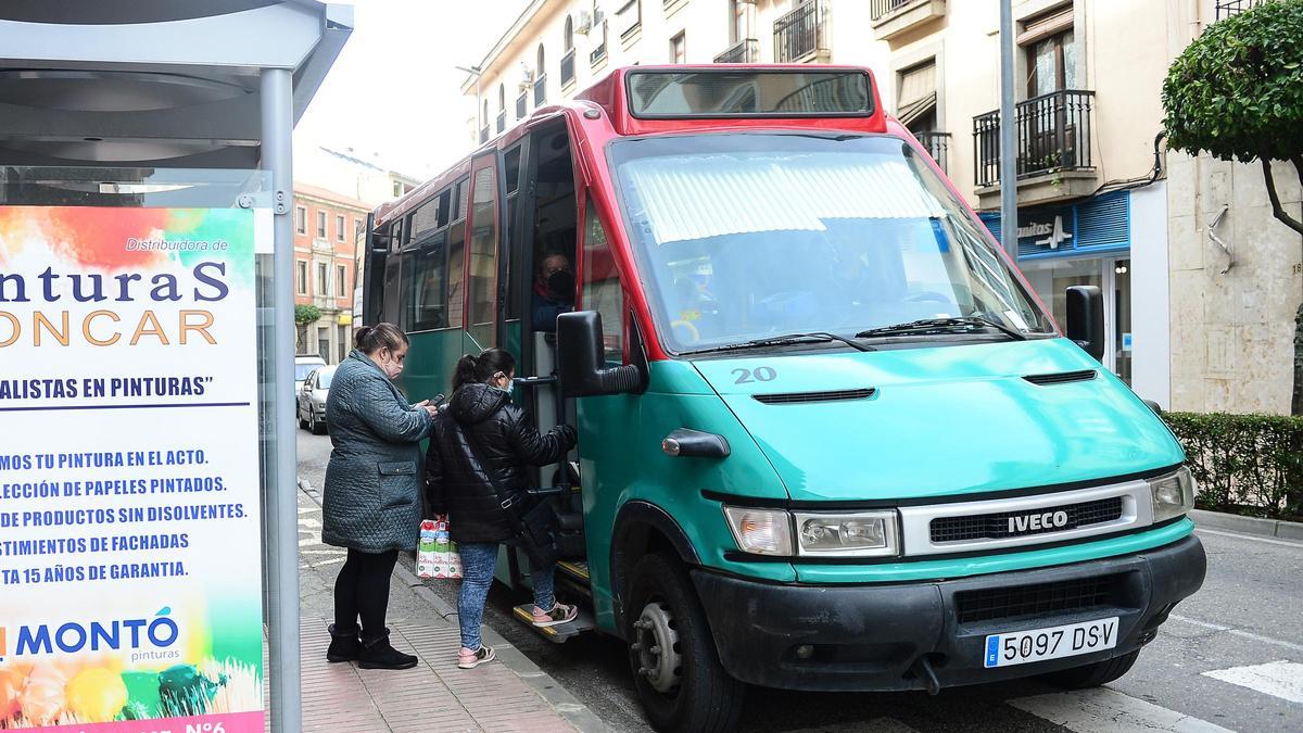 Una marquesina de autobús y con usuarias subiendo al vehículo.