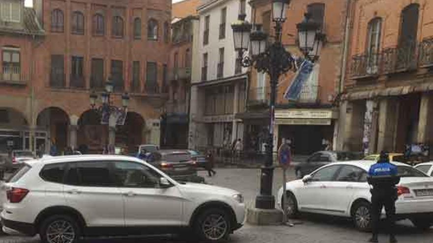 Dos policías multan a dos vehículos en la plaza mayor el miércoles al mediodía.