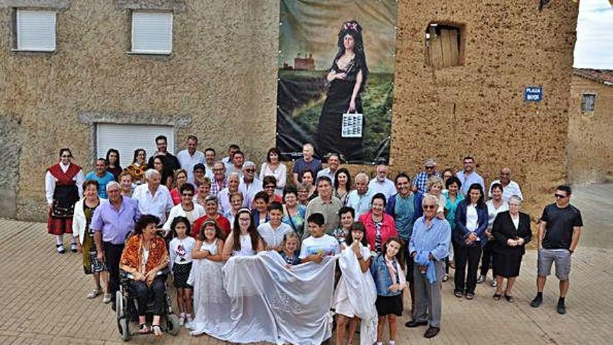 Foto de familia del vecindario con uno de los murales al fondo.