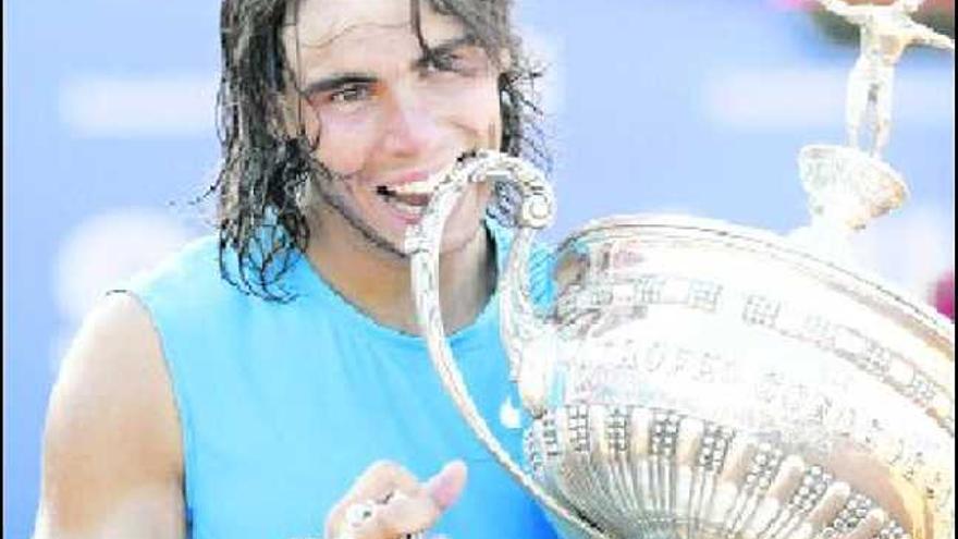 Rafa Nadal, en un gesto característico, simula morder el trofeo conseguido en el Godó tras superar a David Ferrer.