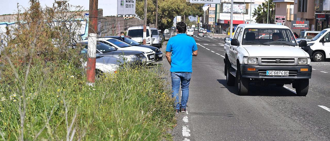 Los coches aparcados en el arcén y las hierbas que crecen en él obligan a los vecinos a utilizar la calzada para transitar por la recta de Los Tarahales. | | JUAN CARLOS CASTRO