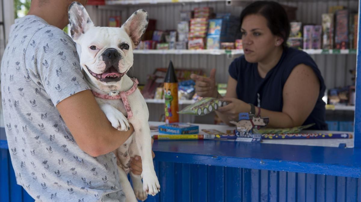 Un dueño en una tienda de petardos, con su perro en brazos