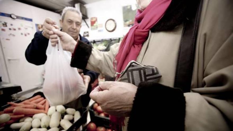 Una mujer compra verduras en un puesto de un mercado de Alicante.