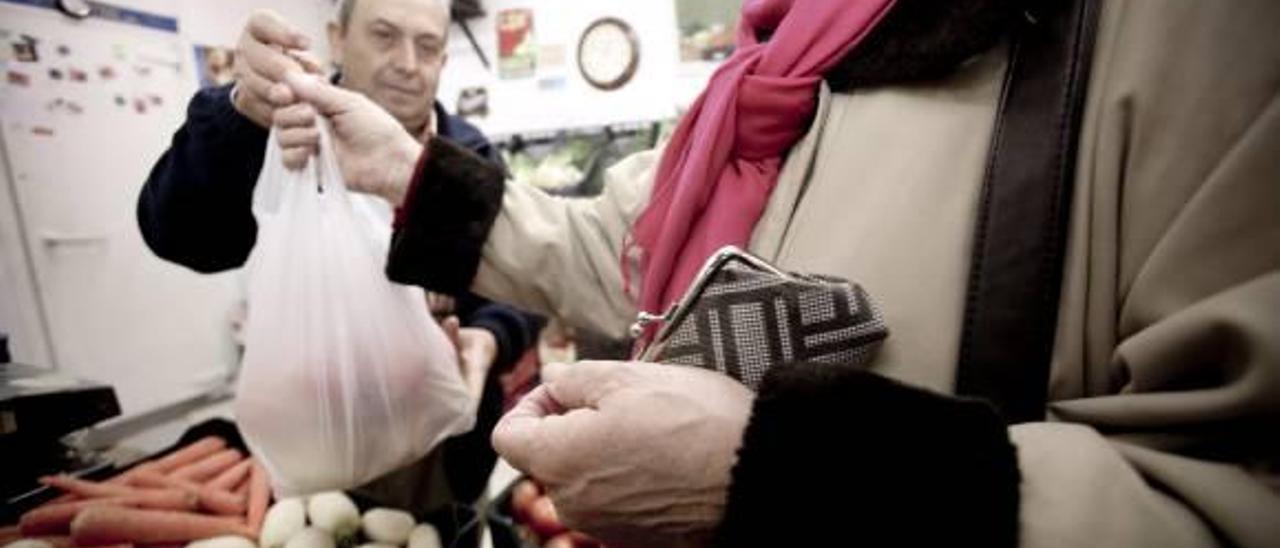 Una mujer compra verduras en un puesto de un mercado de Alicante.