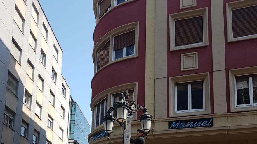 El hombre que llegó a la calle la Cámara a colocar carteles electorales minutos antes del paso del desfile de carrozas del Bollo,en plena faena.