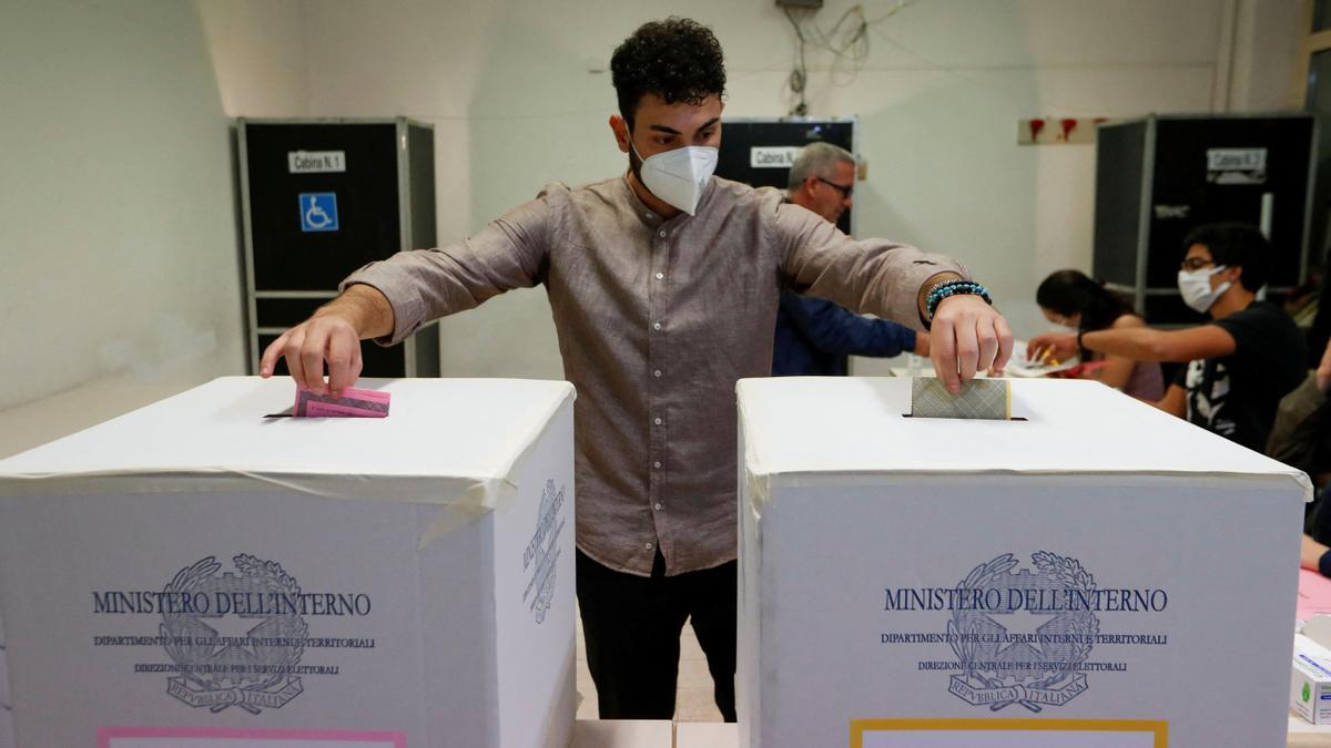 Un hombre deposita las papeletas en las urnas, en un colegio electoral durante las elecciones anticipadas, en Roma, Italia.