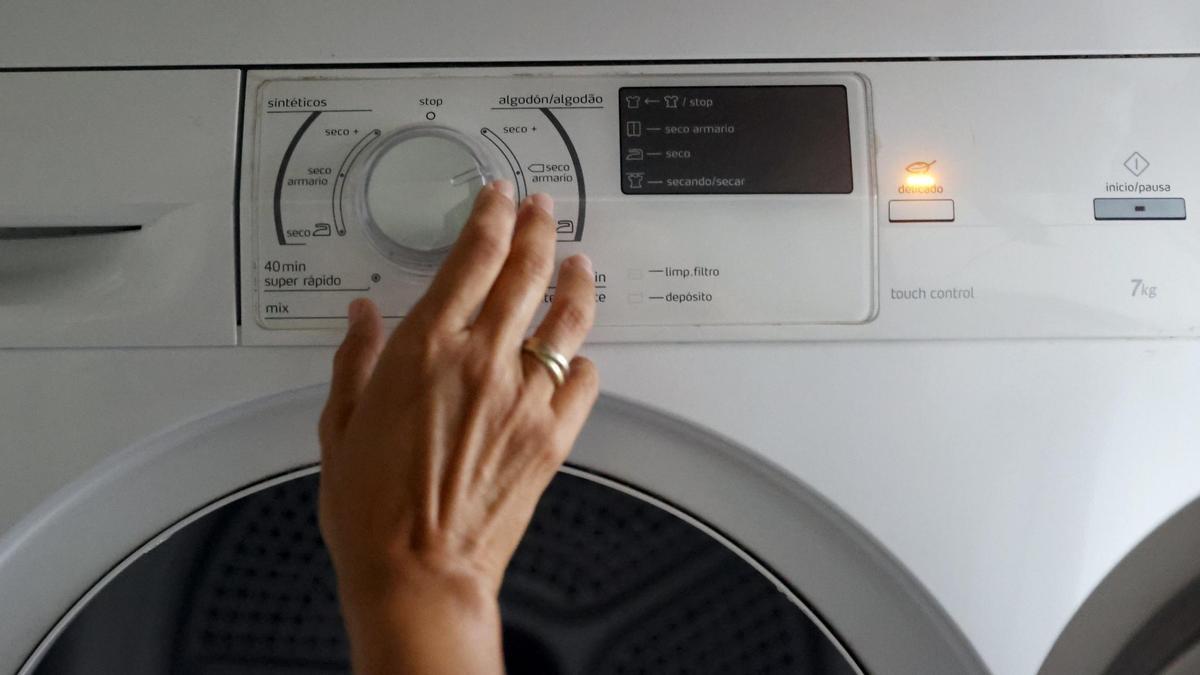 Una mujer programa una lavadora.