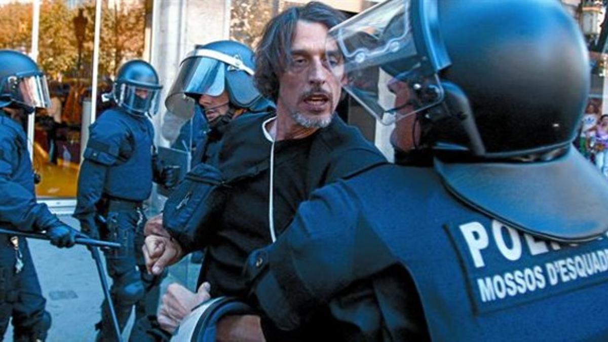 Pugna entre un agente de la policía y un manifestante, en el paseo de Gràcia, el pasado miércoles, en el transcurso de la algarada que sucedió al desalojo de la sede del Banesto.