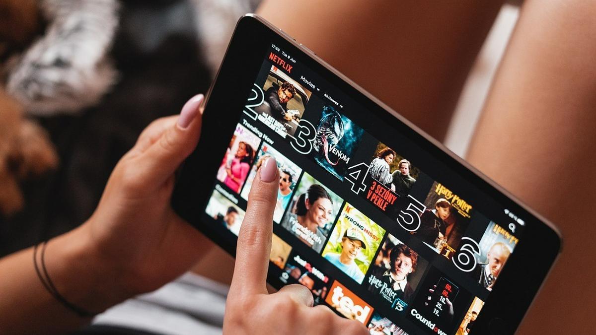 Una mujer selecciona contenido de Netflix en una tablet