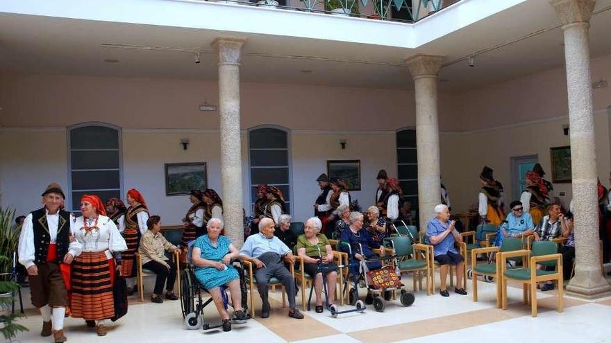 Los mayores contemplan la actuación del grupo de folclore tradicional.