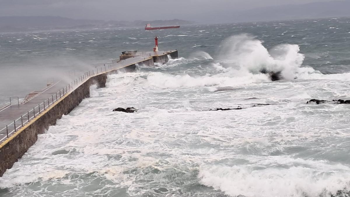Fuerte oleaje ayer en el muelle de Ons y uno de los mercantes fondeados al abrigo de la isla.
