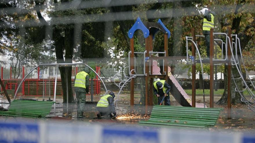 Los trabajadores, al otro lado del vallado, desmontando estructuras de juego.