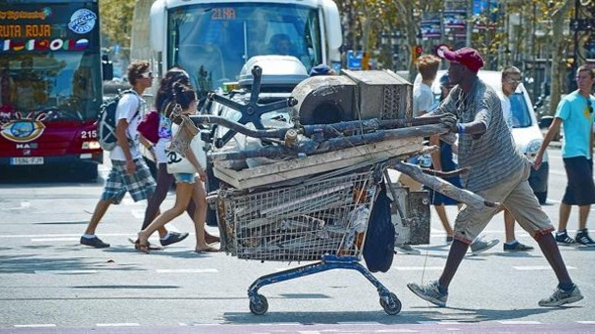 MISERIA A CUESTAS. Un inmigrante africano traslada chatarra por una calle de Barcelona.