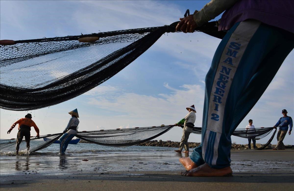 Los pescadores tiran de sus redes de pesca a lo largo de la costa en Banda Aceh, Indonesia.