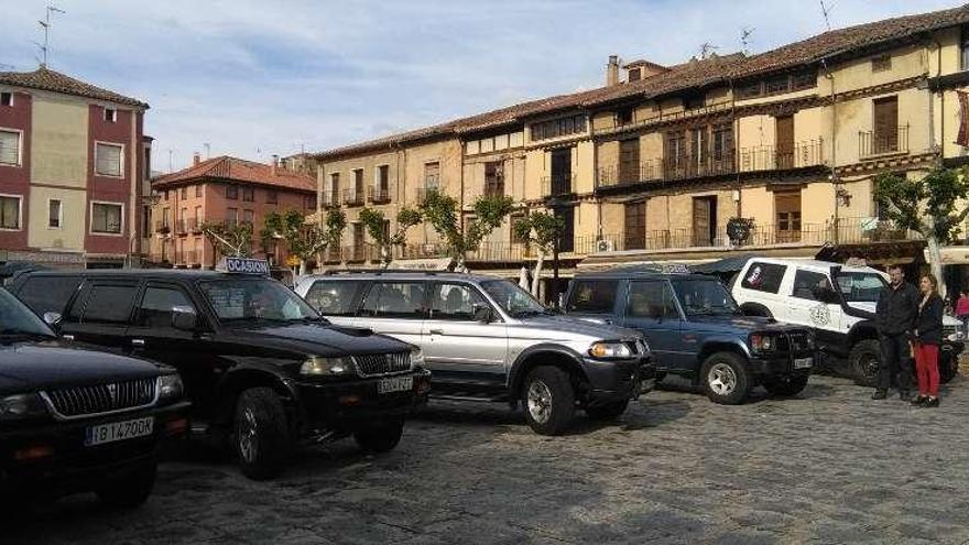 Dos personas contemplan, en la fotografía de arriba, los vehículos de uno de los expositores participantes en la feria y situados en la plaza de La Glorieta. En la fotografía de la izquierda, autoridades, representantes de las entidades organizadoras y expositores inauguran el certamen que durante todo el fin de semana se podrá visitar en Toro .