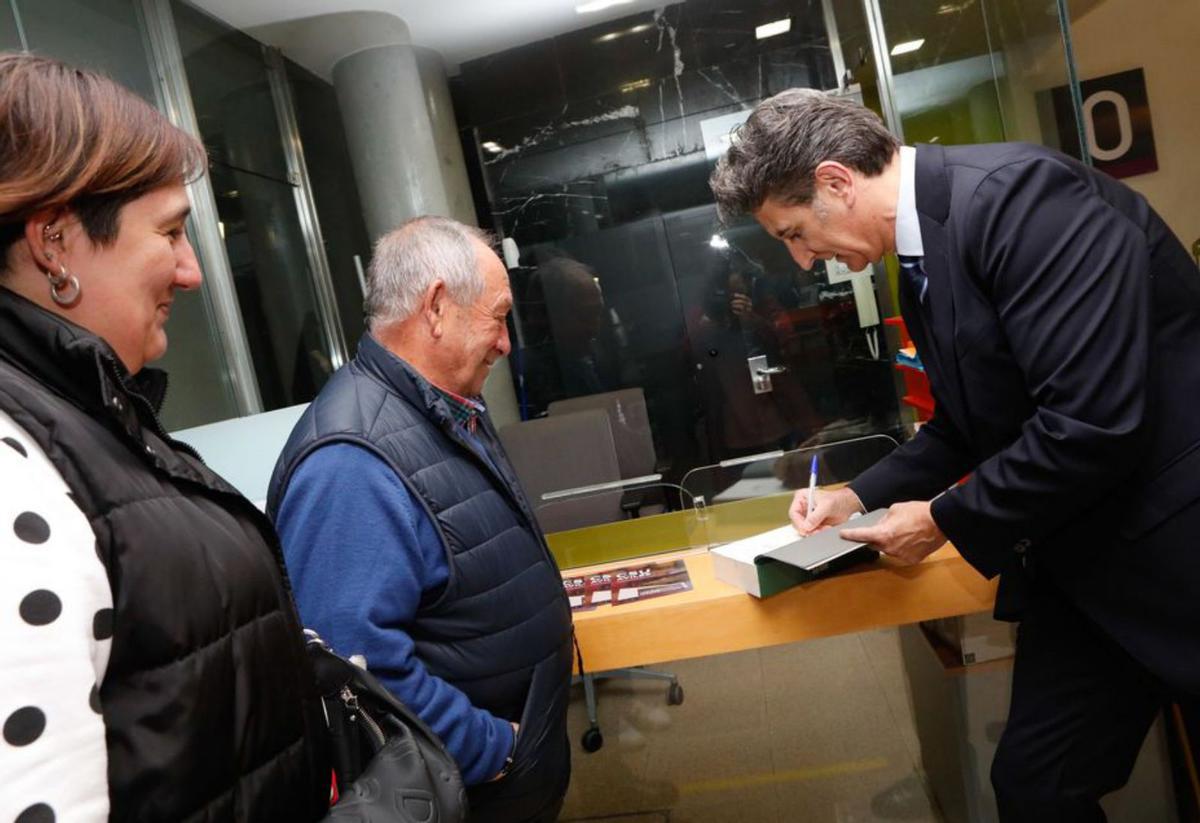 Juan Carlos De la Madrid dedica un libro a unos asistentes al acto. | M. V.