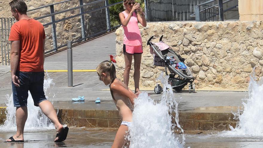 Turistas refrescándose del calor en una fuente de Elche, donde se esperan máximas muy elevadas el próximo fin de semana.