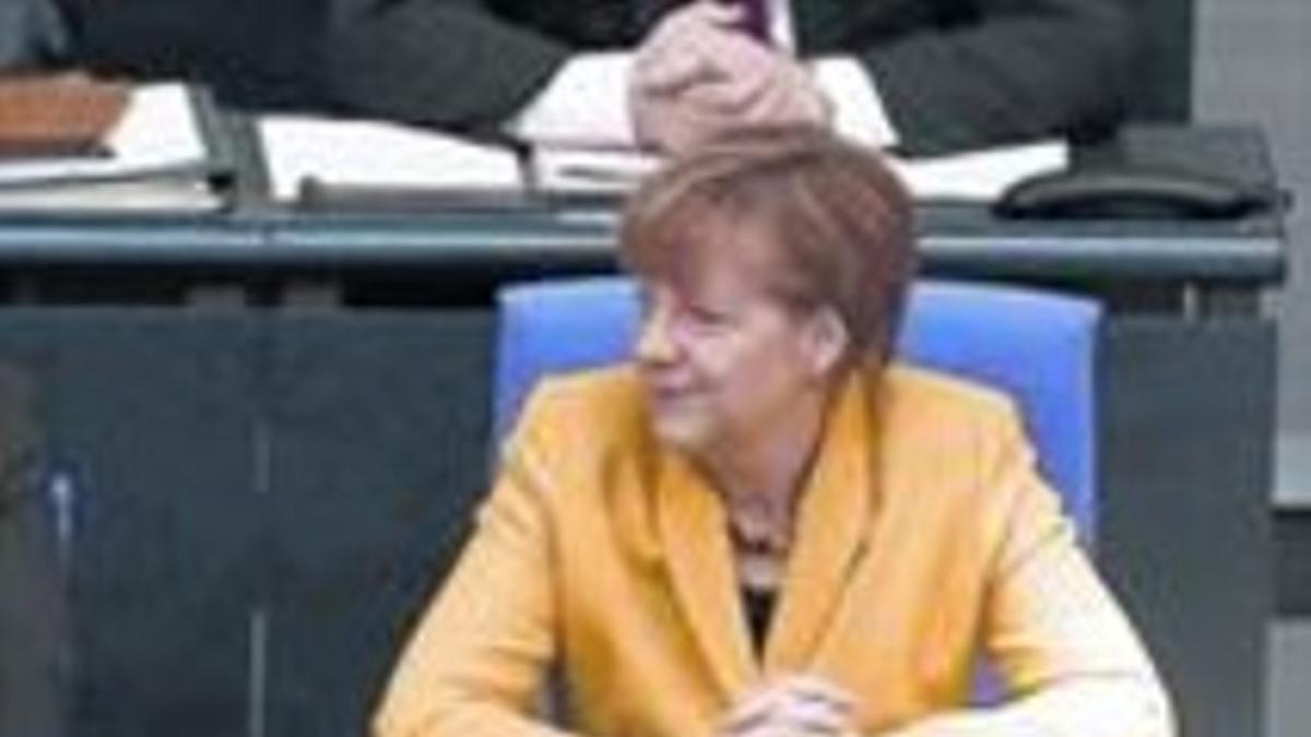 Schäuble abandona la tribuna y pasa ante el escaño de Merkel, ayer.