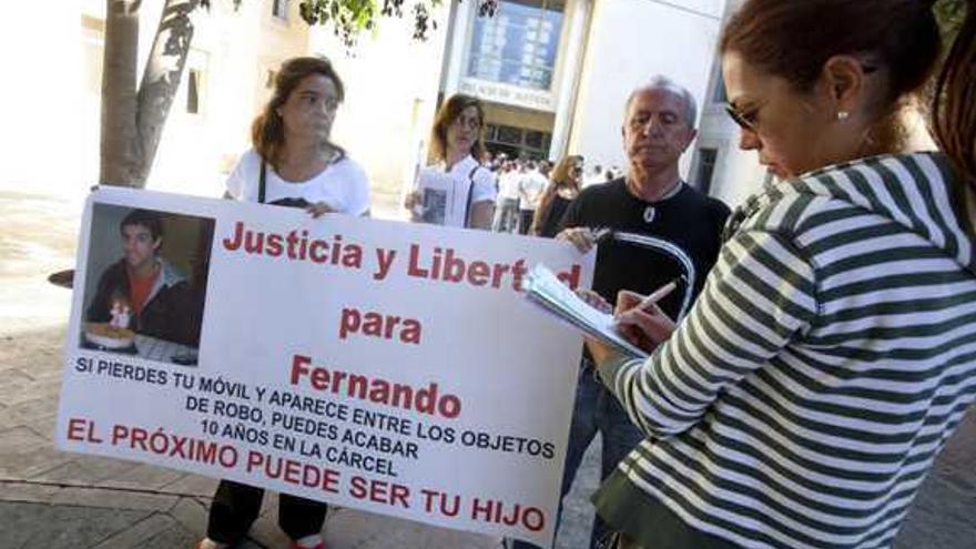 Una joven firma mientras familiares de Fernando sostienen una pancarta ayer en los juzgados.