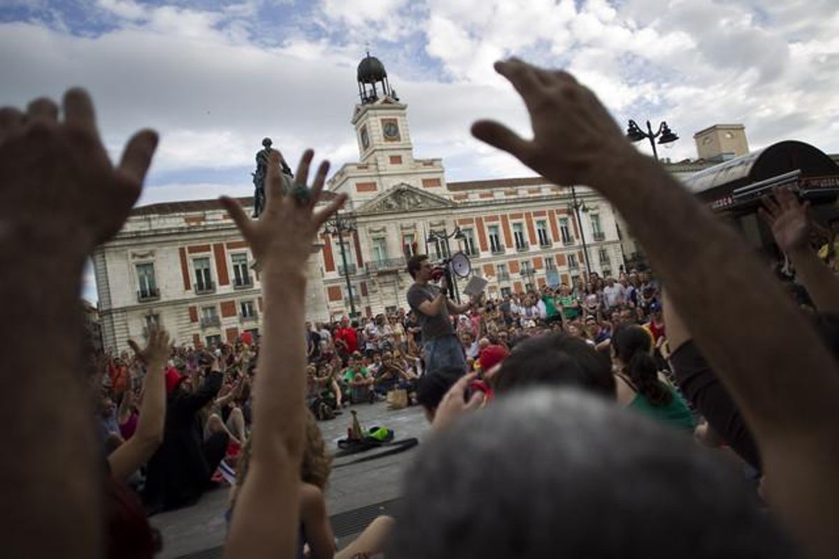 Un grup de persones reunides al centre de Madrid mostren la seva conformitat davant la lectura del fragment d’un llibre en el marc del primer aniversari del 15-M.