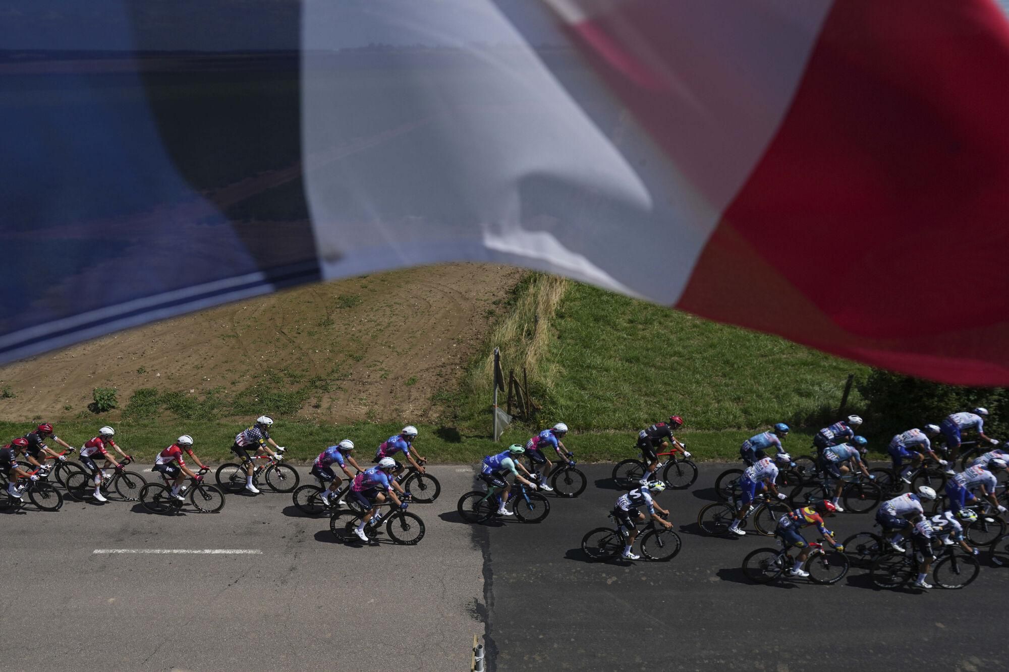 The pack rides under a French flag during the fourth stage of the Tour de France cycling race over 172.2 kilometers (107 miles) with start in Amiens and finish in Rouen, France, Tuesday, July 8, 2025. (AP Photo/Thibault Camus) Associated Press / LaPresse Only italy and spain. EDITORIAL USE ONLY/ONLY ITALY AND SPAIN