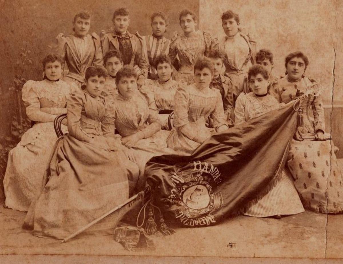 Las amigas de María Álvarez y Suárez posan con la bandera que han bordado.