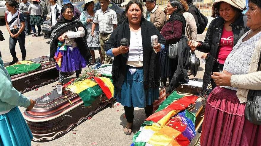 Varias mujeres rodean los féretros de los muertos en los enfrentamientos con policía y ejército ante el Instituto de Investigaciones Forenses de Cochabamba. // Efe