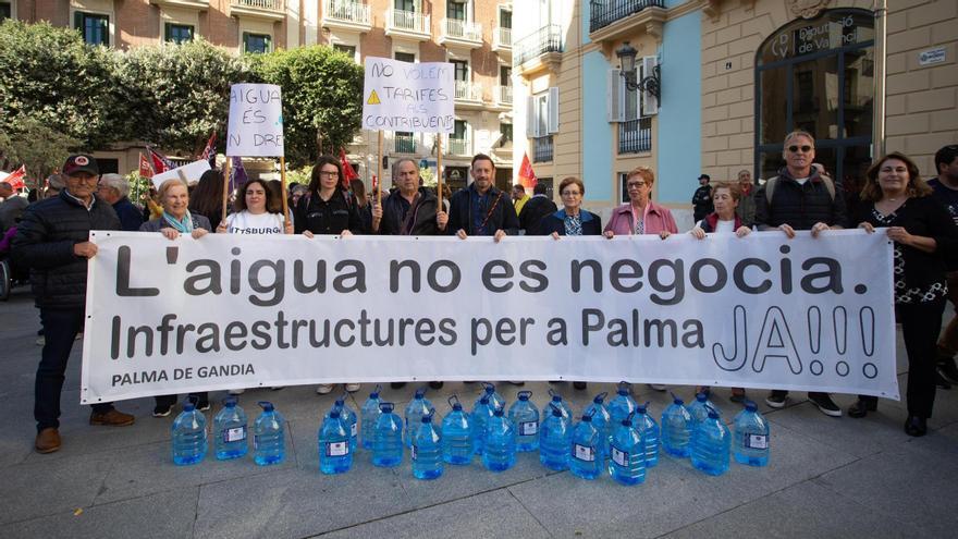 Vecinos y vecinas de Palma, ante la sede de la Diputación, con garrafas como las que reciben para consumir