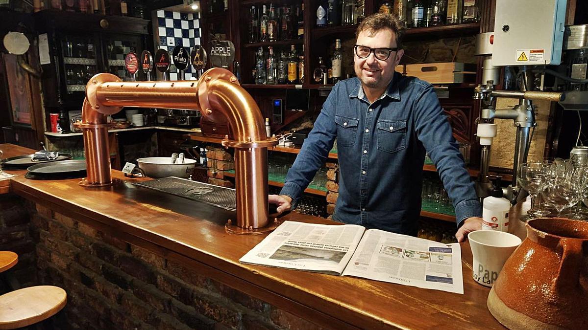 Hugo Suárez lee el periódico en la barra de su establecimiento, en La Felguera. | M. Á. G.