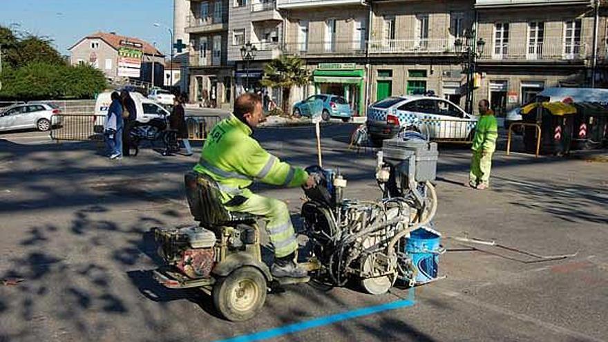 Unos operarios pintan las plazas de la zona azul, ayer, en el aparcamiento del Campo da Feira