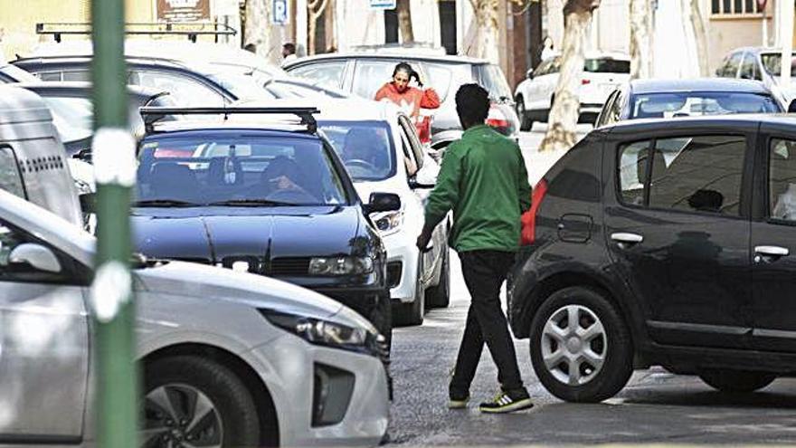 Dos aparcacoches ilegales dan indicaciones a los conductores para que estacionen en una calle del centro de Murcia.