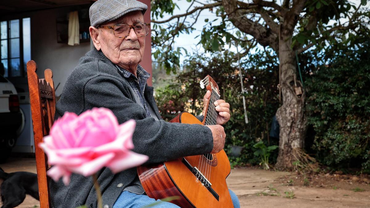 Julio López sentado en el patio de su casa, tocando la guitarra